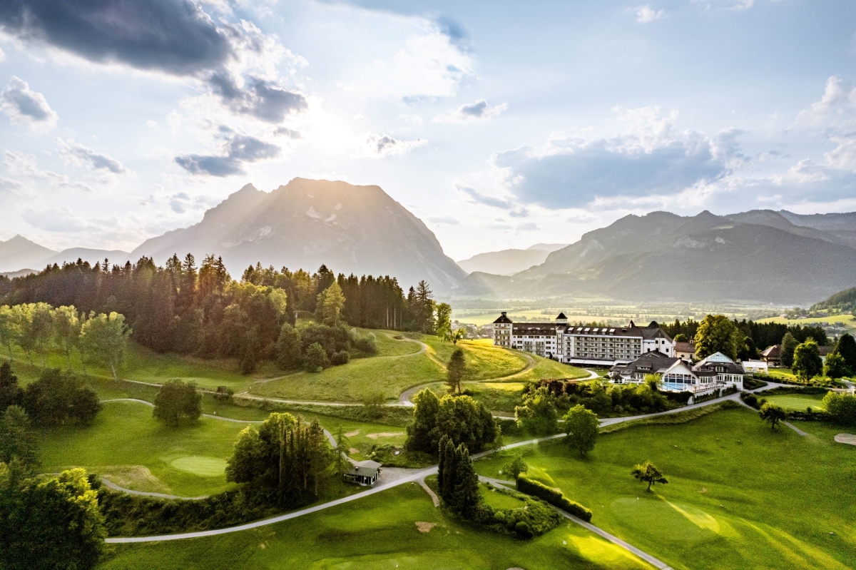 IMLAUER Hotel Schloss Pichlarn mit davor liegendem Golfplatz und dem Grimming im HIntergrund